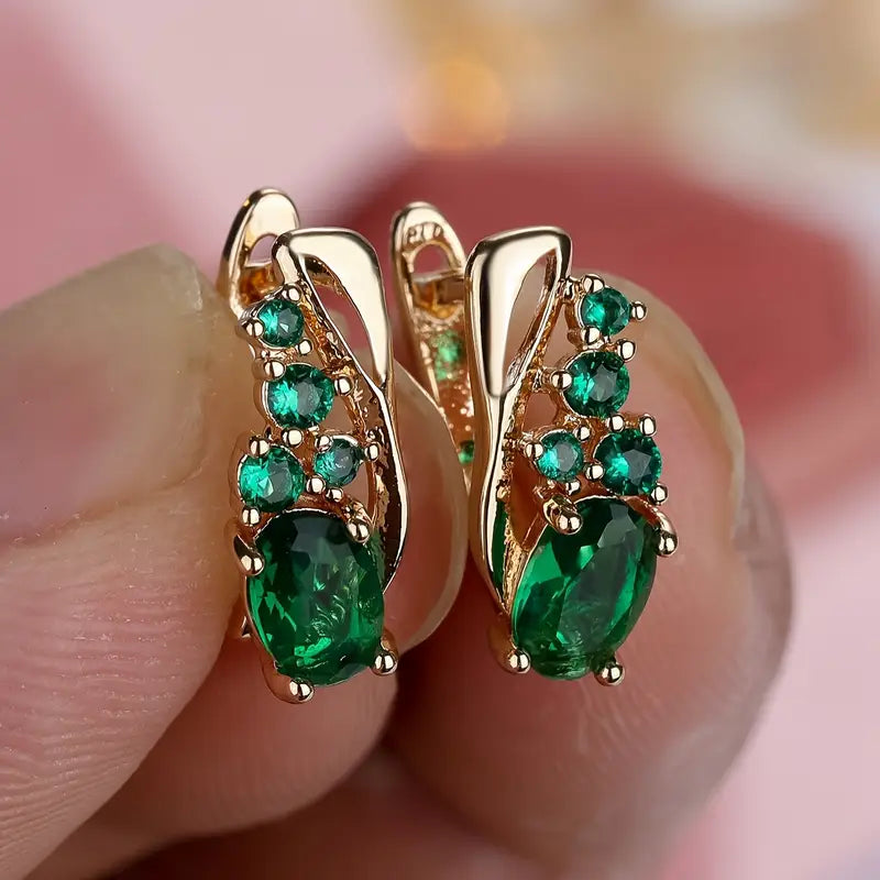 Elegant earrings with emerald-like green stones in a golden hue