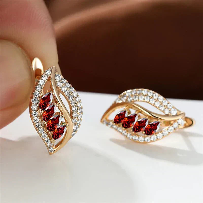 Shiny leaf-shaped earrings with teardrop-shaped red stones and sparkling cubic zirconia