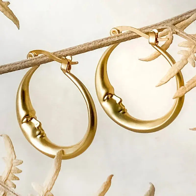 Elegant gold-coloured hoop earrings featuring an antique moon face design