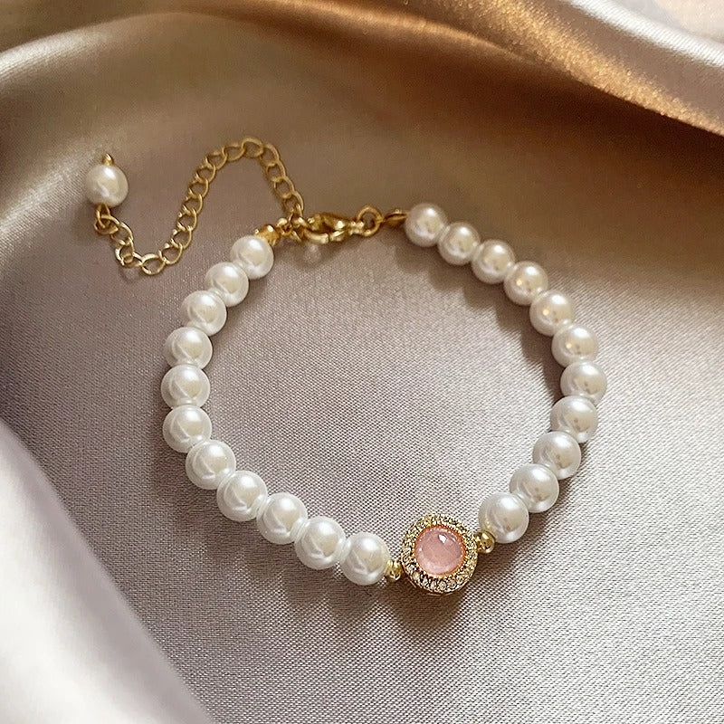 An elegant pearl bracelet with pink stone details and an extendable chain