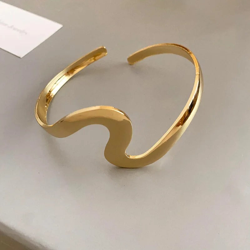 An elegant open bracelet with a wavy, sparkling design