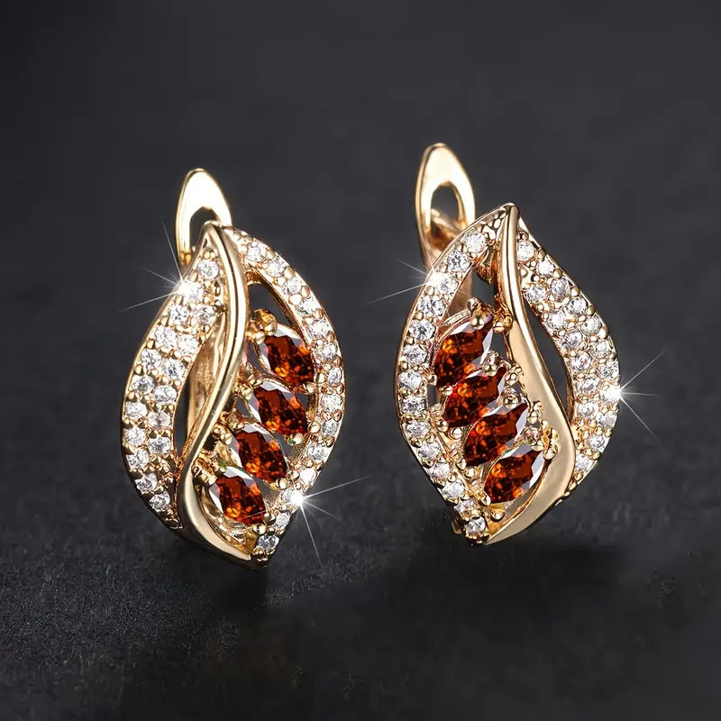 Shiny leaf-shaped earrings with teardrop-shaped red stones and sparkling cubic zirconia