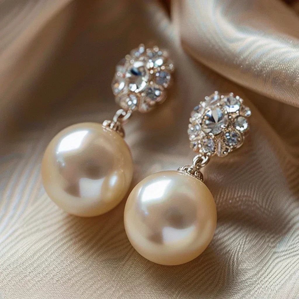 Elegant earrings featuring large pearls and radiant rhinestone flowers