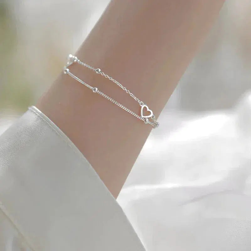 An elegant double-chain bracelet featuring hearts and delicate beads