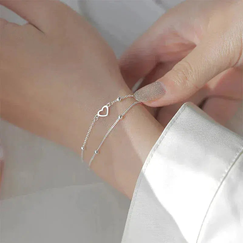 An elegant double-chain bracelet featuring hearts and delicate beads