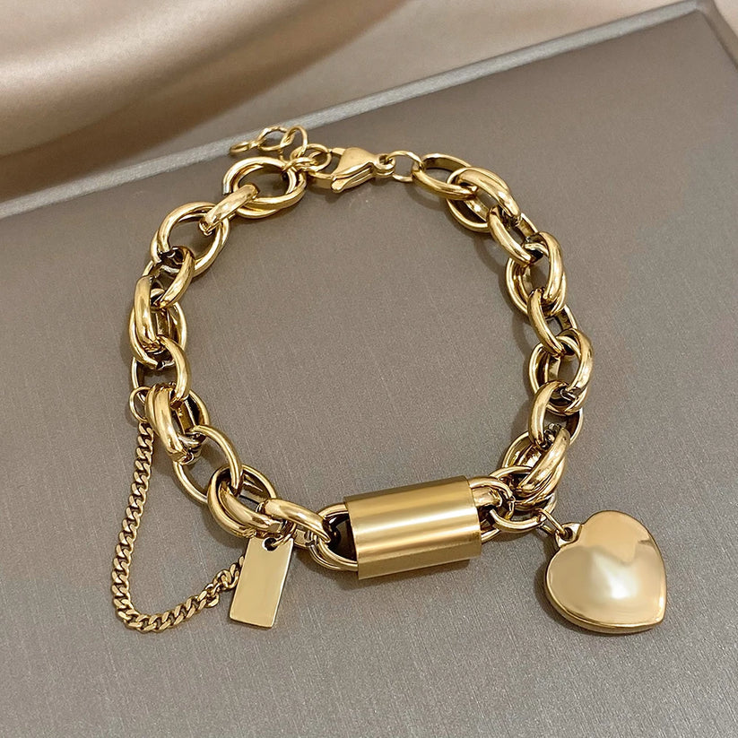Modern bracelet with a chunky link chain and a heart and cylinder pendant