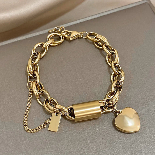 Modern bracelet with a chunky link chain and a heart and cylinder pendant