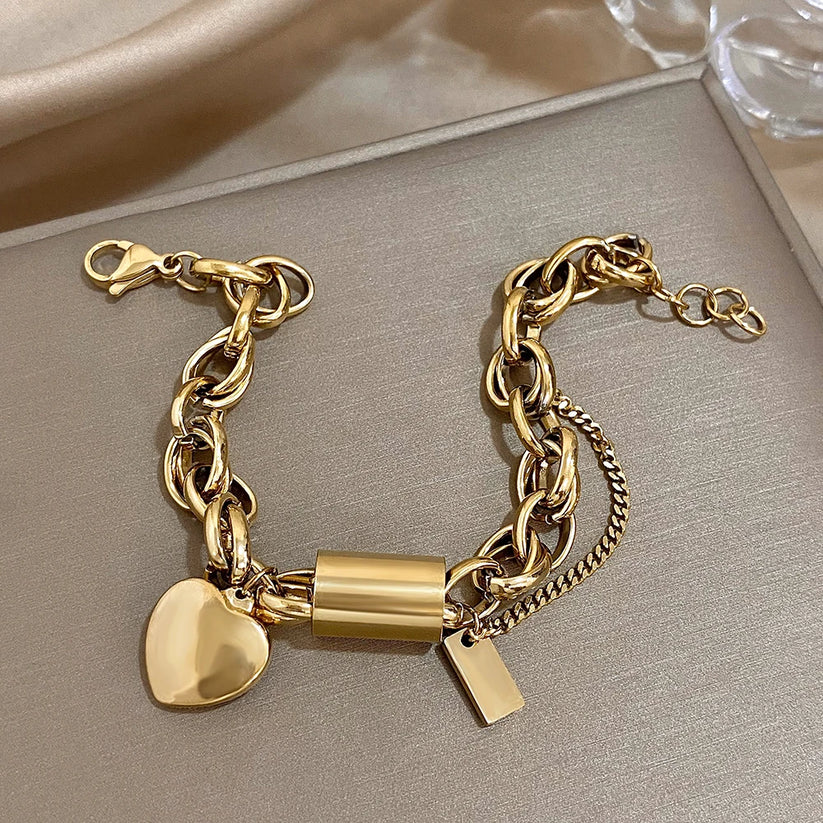 Modern bracelet with a chunky link chain and a heart and cylinder pendant