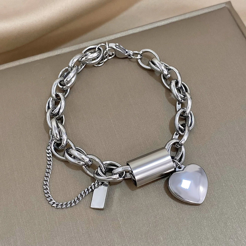 Modern bracelet with a chunky link chain and a heart and cylinder pendant