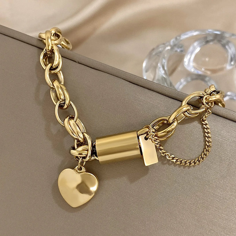 Modern bracelet with a chunky link chain and a heart and cylinder pendant