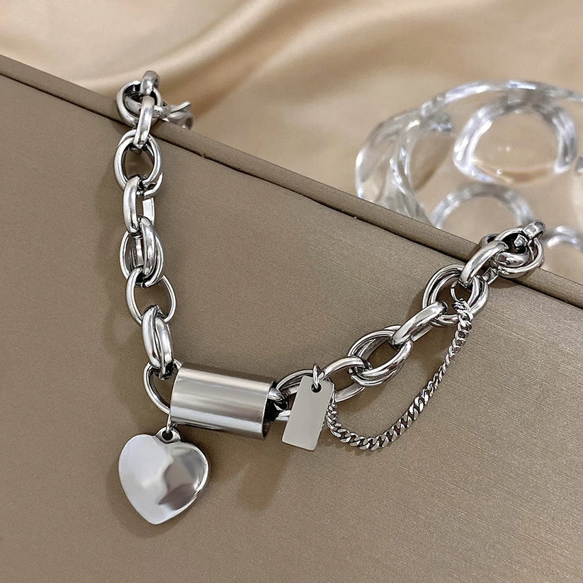 Modern bracelet with a chunky link chain and a heart and cylinder pendant