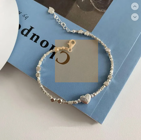 A glamorous bracelet featuring geometric elements, heart-shaped details and pearls
