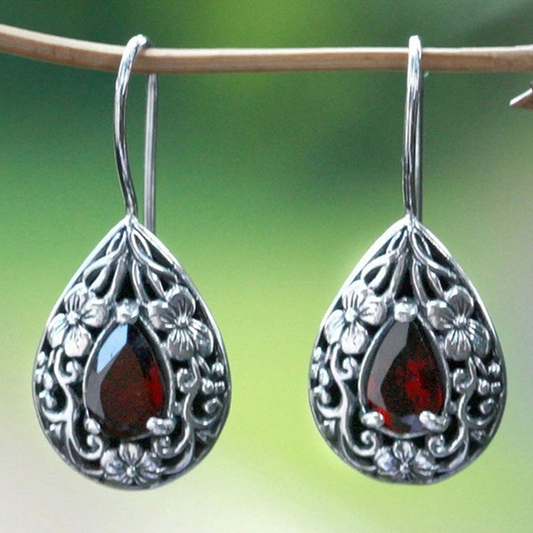 Silver colored teardrop earrings with red garnet and a floral design