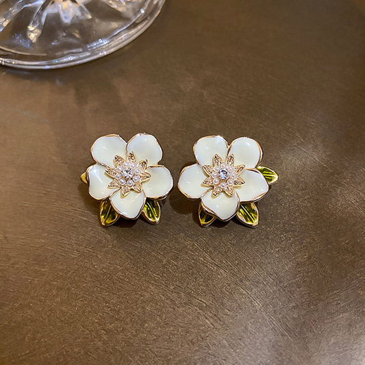 Earrings featuring cream-coloured enamelled flowers with sparkling cubic zirconia stones and leaves
