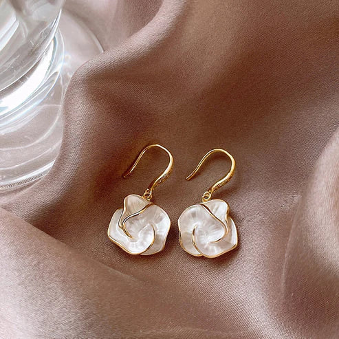 Elegant flower earrings with mother-of-pearl details set against shiny satin