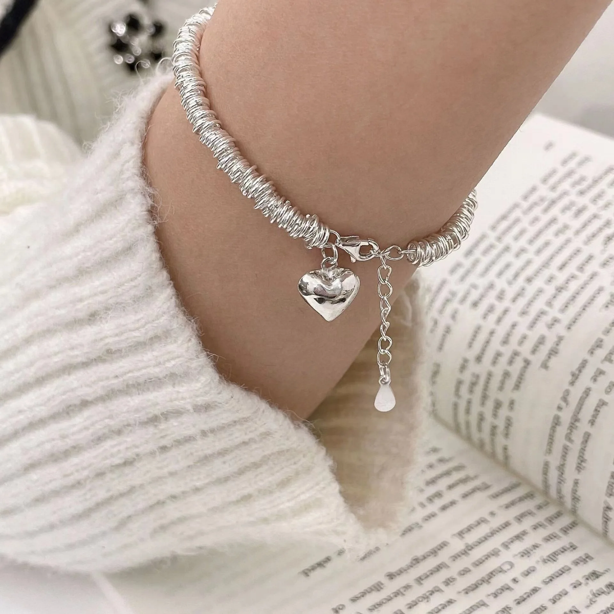 An elegant bracelet featuring a heart-shaped pendant and a spiral ‘resort’ design