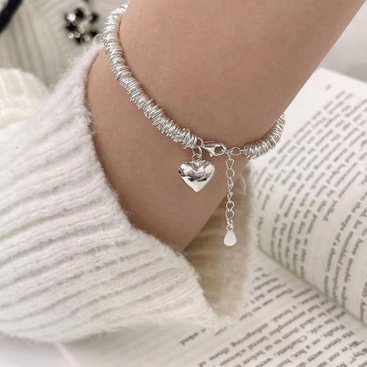 An elegant bracelet featuring a heart-shaped pendant and a spiral ‘resort’ design