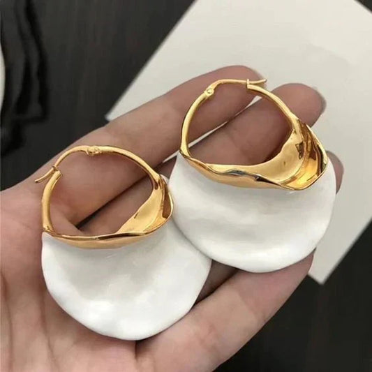 Curved hoop earrings with a gold-tone finish and a matt white disc