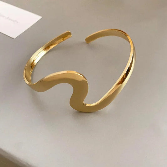 An elegant open bracelet with a wavy, sparkling design